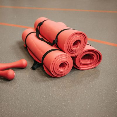 Roll of natural rubber yoga mat on a floor.